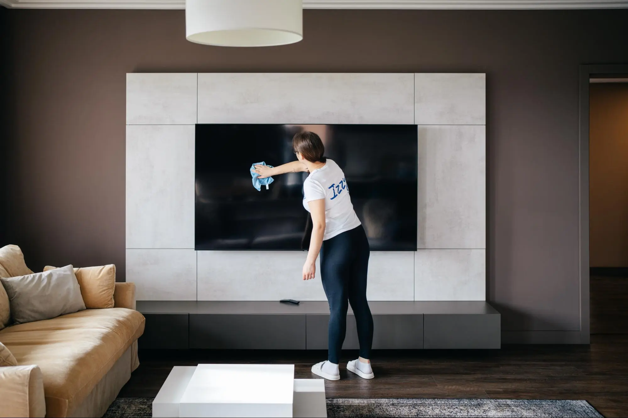 paní na úklid čistí televizi při úklidu domácnosti